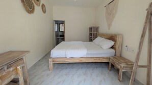 A bedroom with a wooden bed, a wooden nightstand, a small wooden table, and a wardrobe. - Luma Guesthouse by Verdana Homes (Tibubeneng)