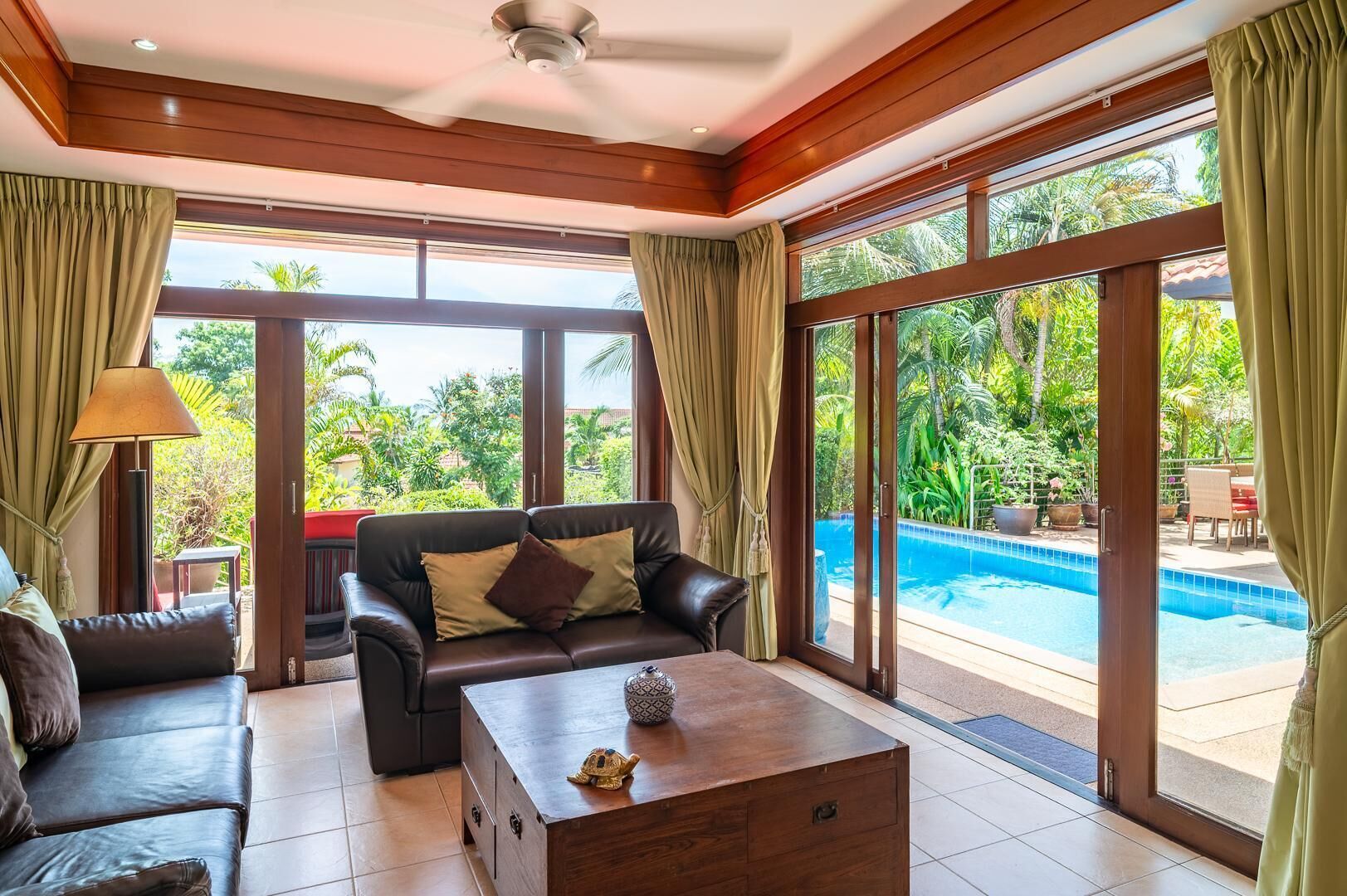 Une pièce spacieuse avec un canapé en cuir, une table basse en bois et une vue sur une piscine.
