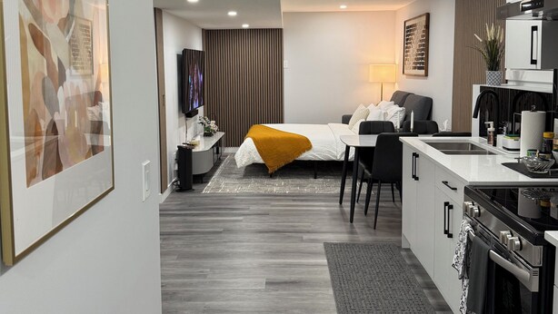 Een moderne, compacte leefruimte met een kitchenette, een eethoek en een slaapkamer.