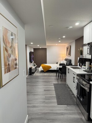 Un espace de vie moderne et compact comprenant un coin cuisine, un espace repas et une chambre.