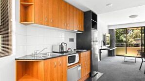 Eine moderne Küche mit Holzausstattung, einem Edelstahlkühlschrank, einer Mikrowelle und einem Spülbecken.
