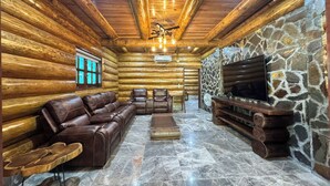A log cabin interior with a stone wall, leather furniture, and a fireplace. - Cendana Trang An Retreat (Hoa Lu)