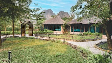 Un resort con cabañas de techo de paja, un camino pavimentado y abundante vegetación.