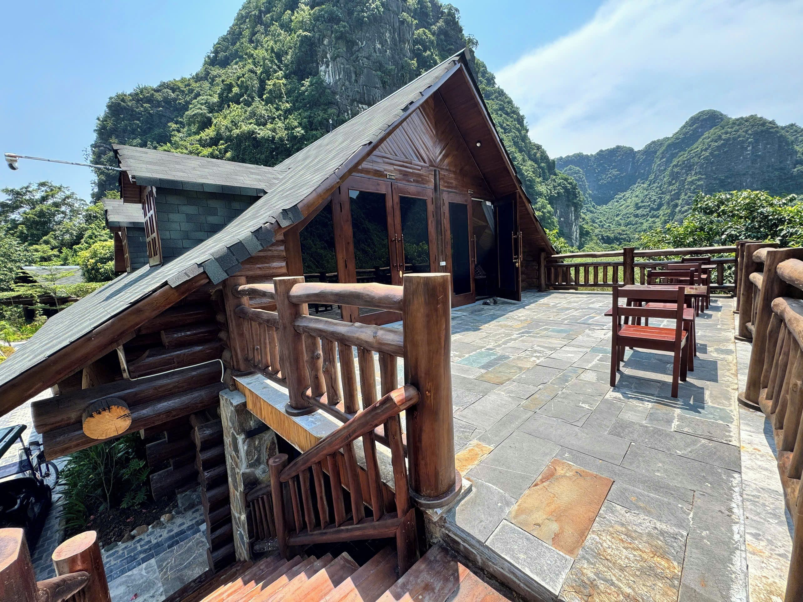 Una cabaña de madera con techo inclinado, piso de piedra y vistas a un paisaje montañoso.