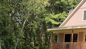A backyard with a fire pit, four Adirondack chairs, and a wooden deck. - Charming 2-bedroom cottage in Roscommon (Roscommon)