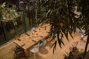 A dining area with a long wooden table, chairs, and hanging pendant lights.