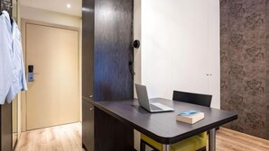 A small room with a desk, chair, and a laptop. There is a door and a wall with a pattern. - Ibis Styles Brussels Centre Stephanie (Brussels)