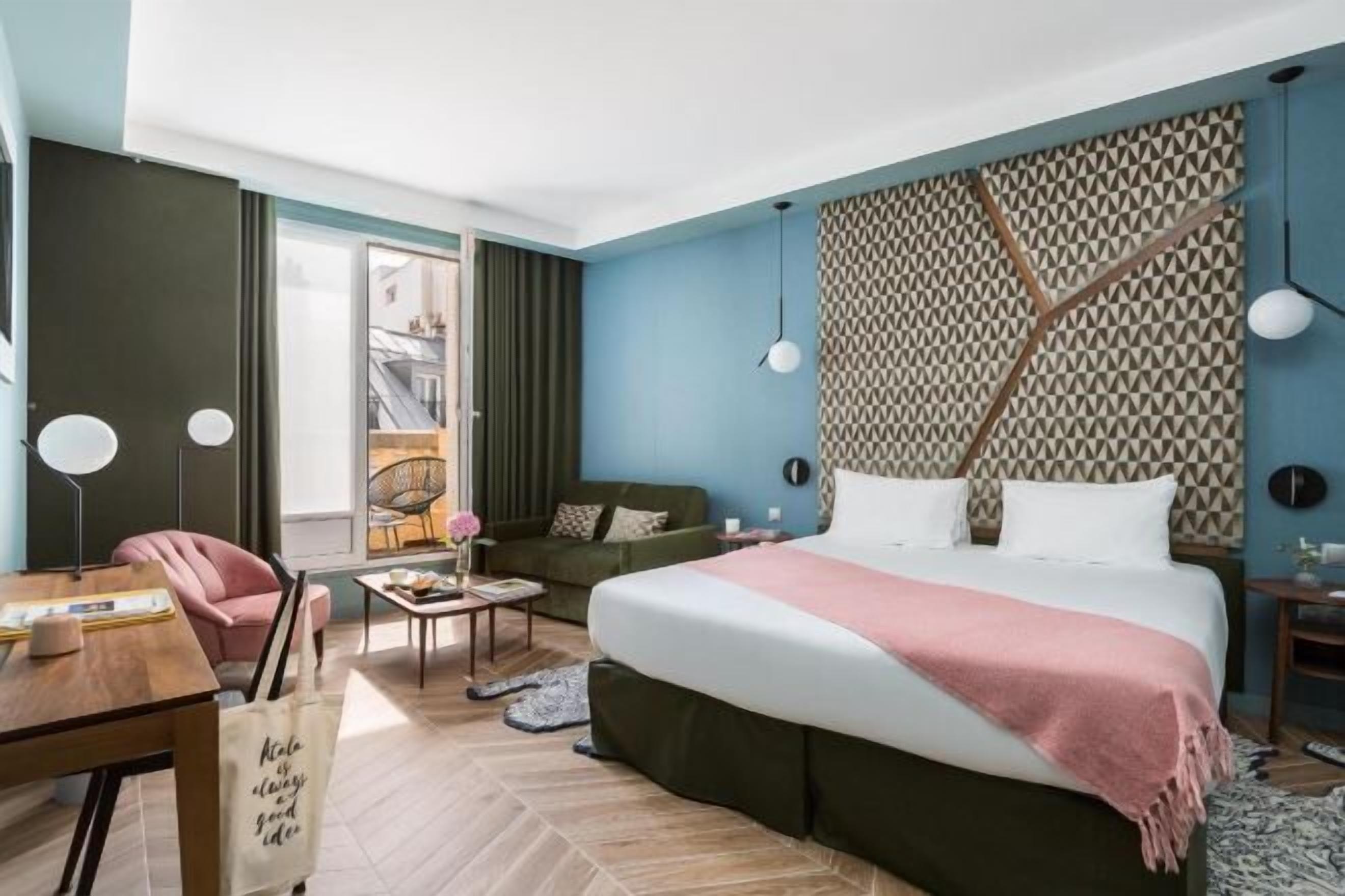 Ein modernes Hotelzimmer mit einem großen Bett, einem Schreibtisch, einem Sessel und einer Couch.