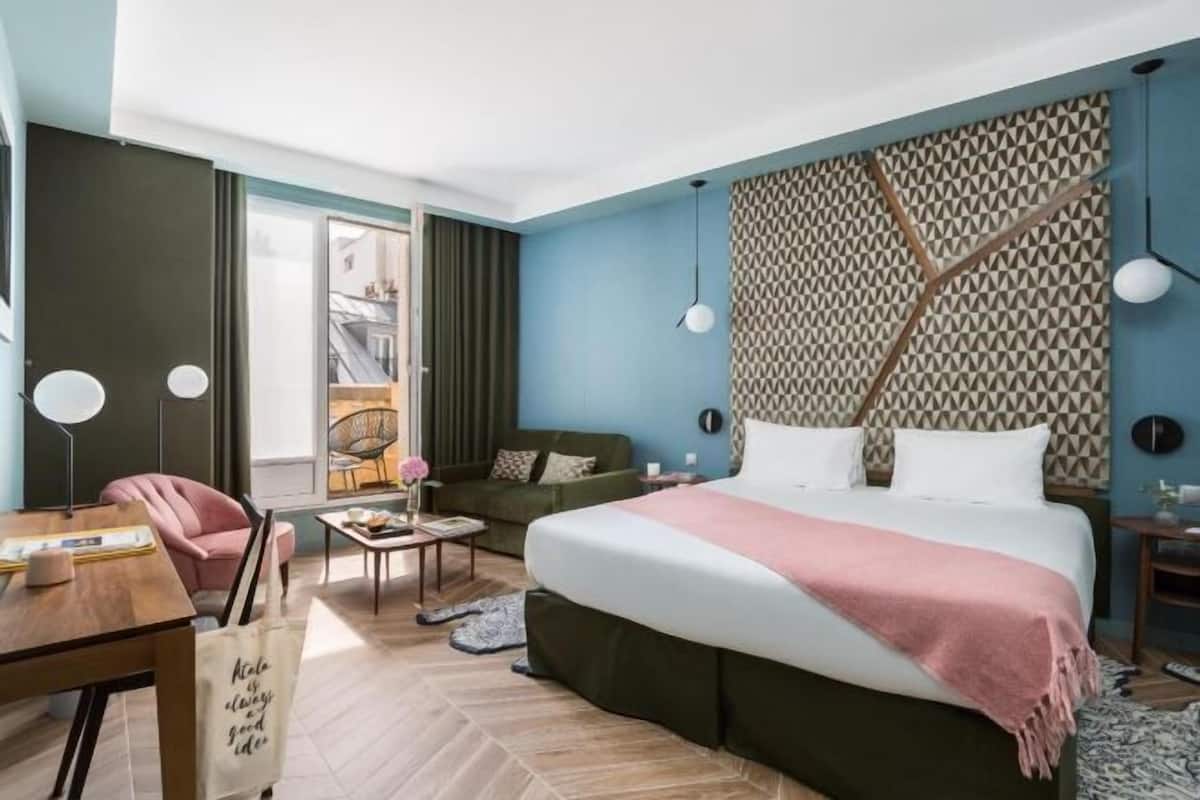 Ett modernt hotellrum med en stor säng, ett skrivbord, en stol och en soffa.