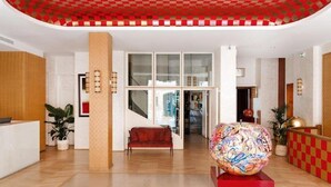 A lobby with a reception desk, a red sofa, a large decorative sphere, and a staircase leading to upper floors.