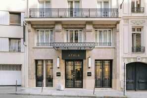 Un bâtiment sur lequel on peut lire l’inscription « ATALA » au-dessus de l’entrée, avec une porte à deux battants et un balcon doté d’une balustrade.