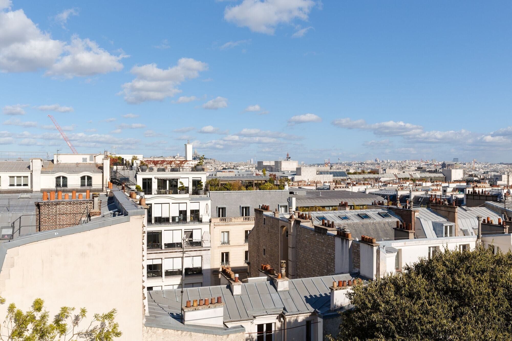 Eine Stadtansicht mit mehreren Gebäuden, darunter ein markantes weißes Gebäude mit Balkon und ein Ziegelhaus.