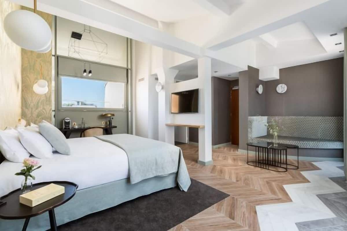 Ett modernt hotellrum med en säng, ett sängbord och en tv.