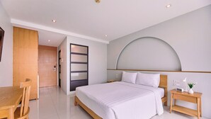 A modern hotel room with a large bed, a wooden nightstand, a desk, and a chair. - Go2bed Pattaya (Pattaya)