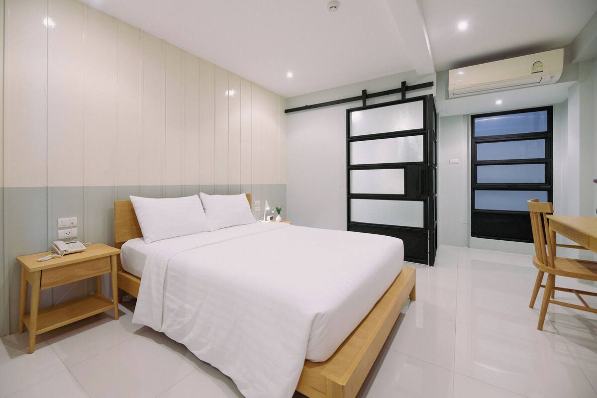 Quarto com cama, mesa de cabeceira e uma cadeira.