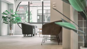 A modern interior with a large window, a potted plant, and a seating area with a sofa and chairs. - Go2bed Pattaya (Pattaya)