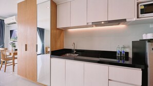 A modern kitchen with white cabinets, a black countertop, and stainless steel appliances. - Go2bed Pattaya (Pattaya)