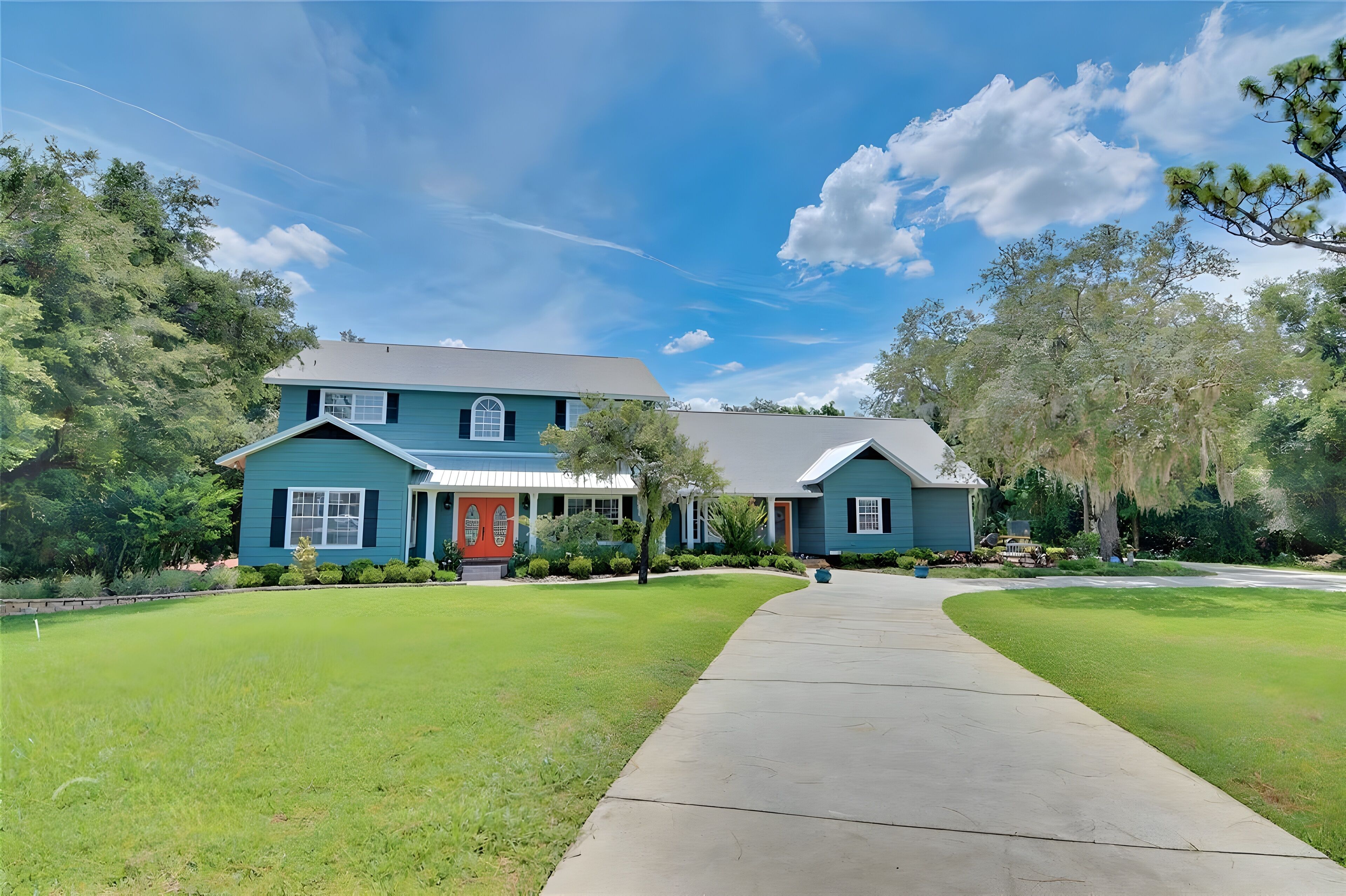 A two-story house with a red door, a covered porch, and a well-maintained lawn.