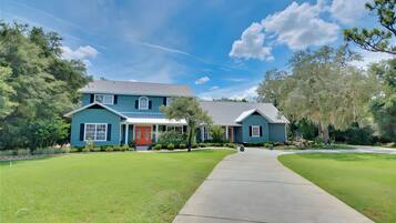 A two-story house with a red door, a covered porch, and a well-maintained lawn.