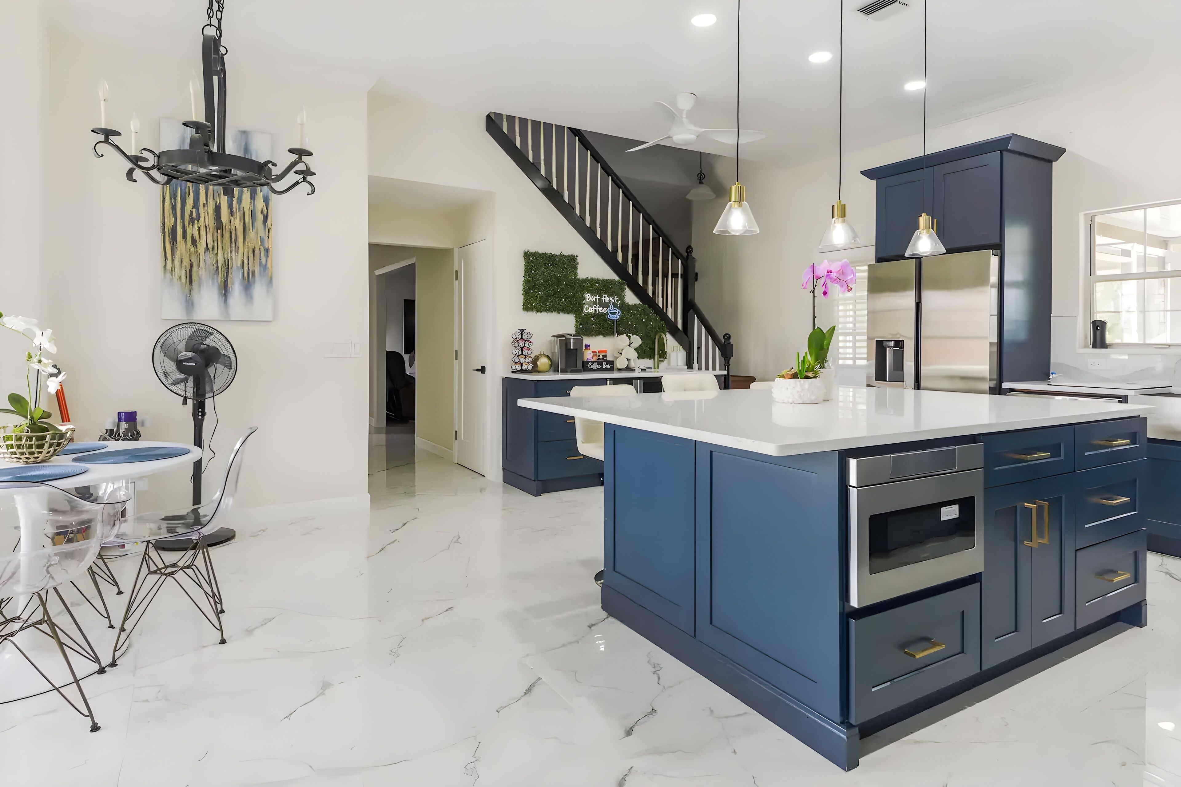 A modern kitchen with a central island, dark blue cabinets, and stainless steel appliances.