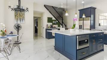 A modern kitchen with a central island, dark blue cabinets, and stainless steel appliances.