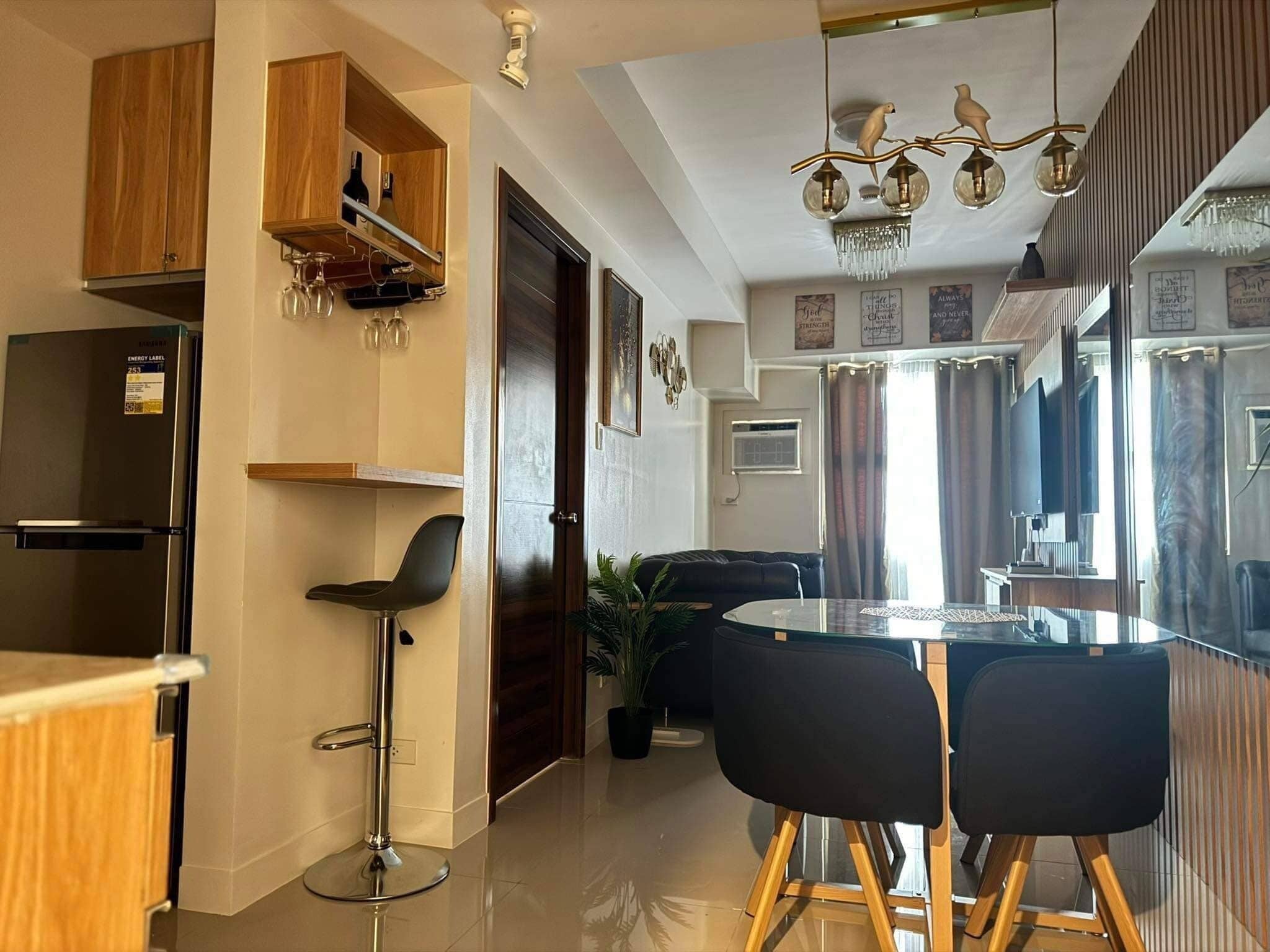 A modern kitchen with wooden cabinets, a built-in wine rack, and a stainless steel refrigerator.