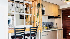 Een moderne keuken met twee zwarte stoelen, houten kasten en een ingebouwd schap met hangende planten.