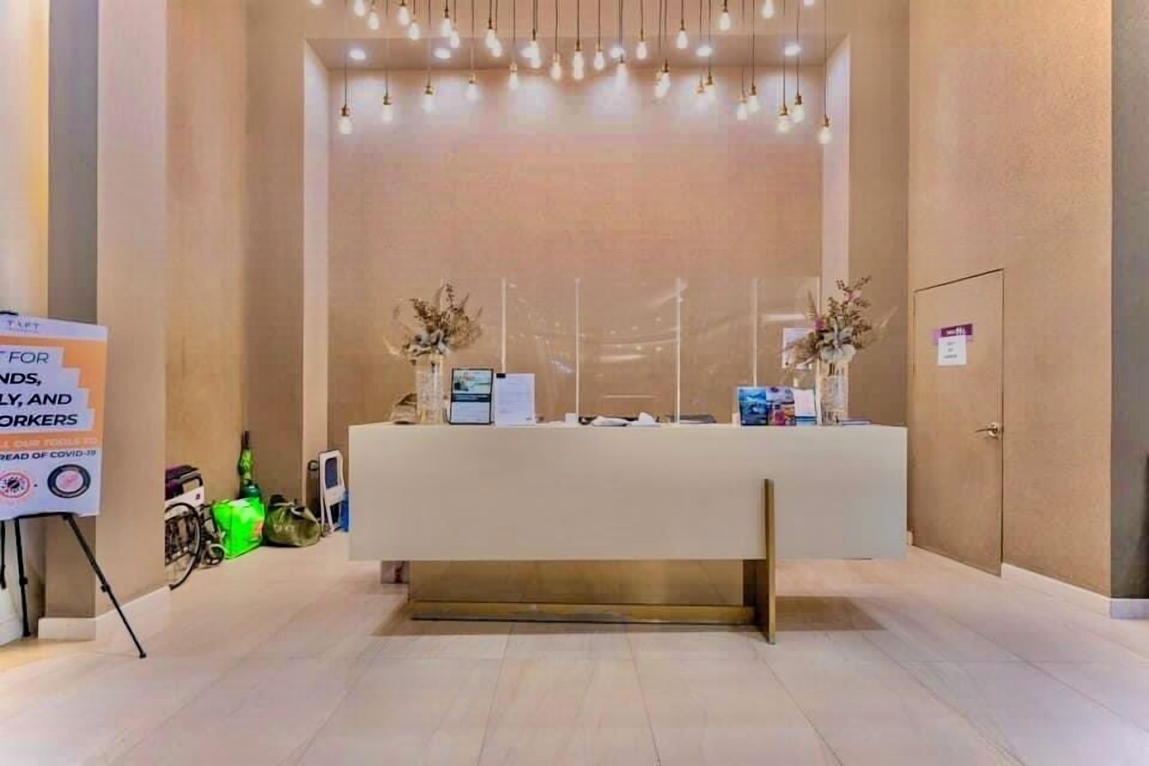 A reception area with a reception desk, a sign for COVID-19 safety, and a wall-mounted information board.