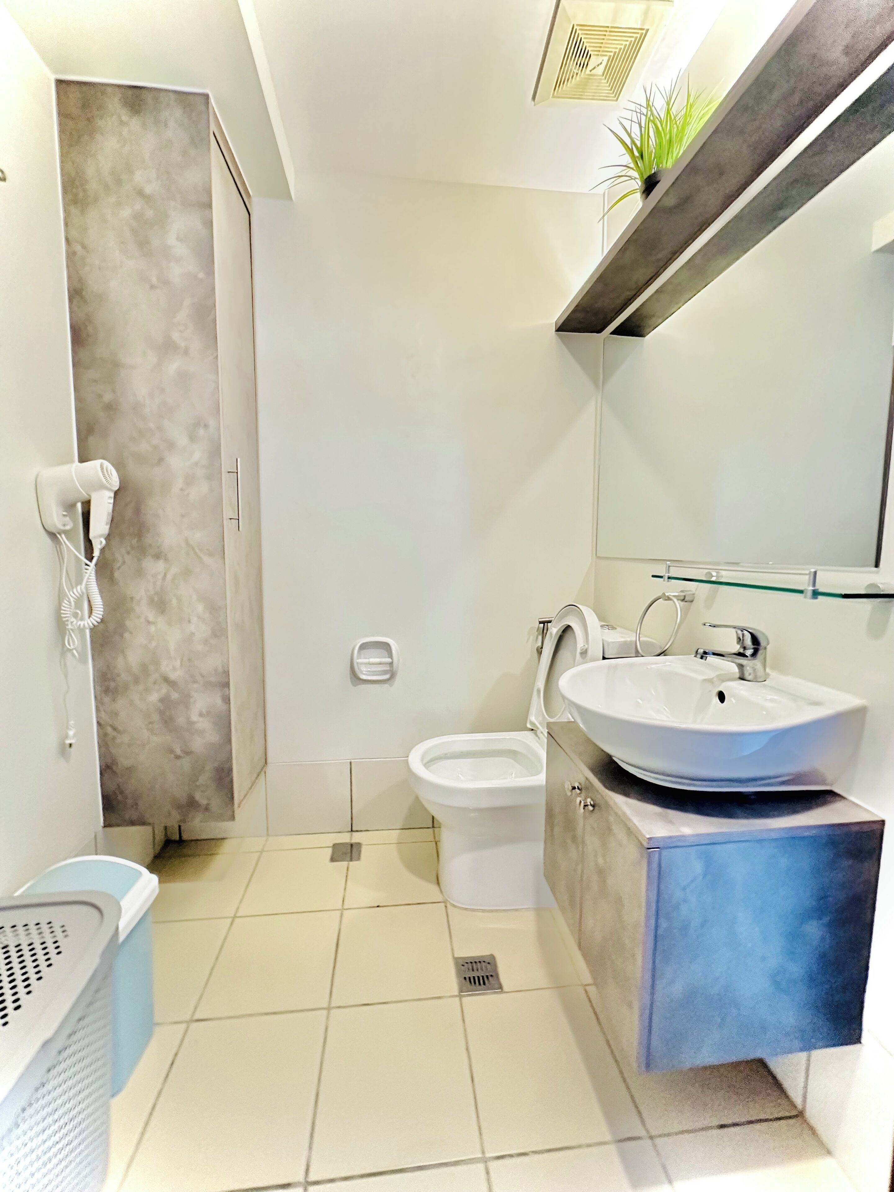 A modern bathroom with a toilet, sink, and hairdryer mounted on the wall.