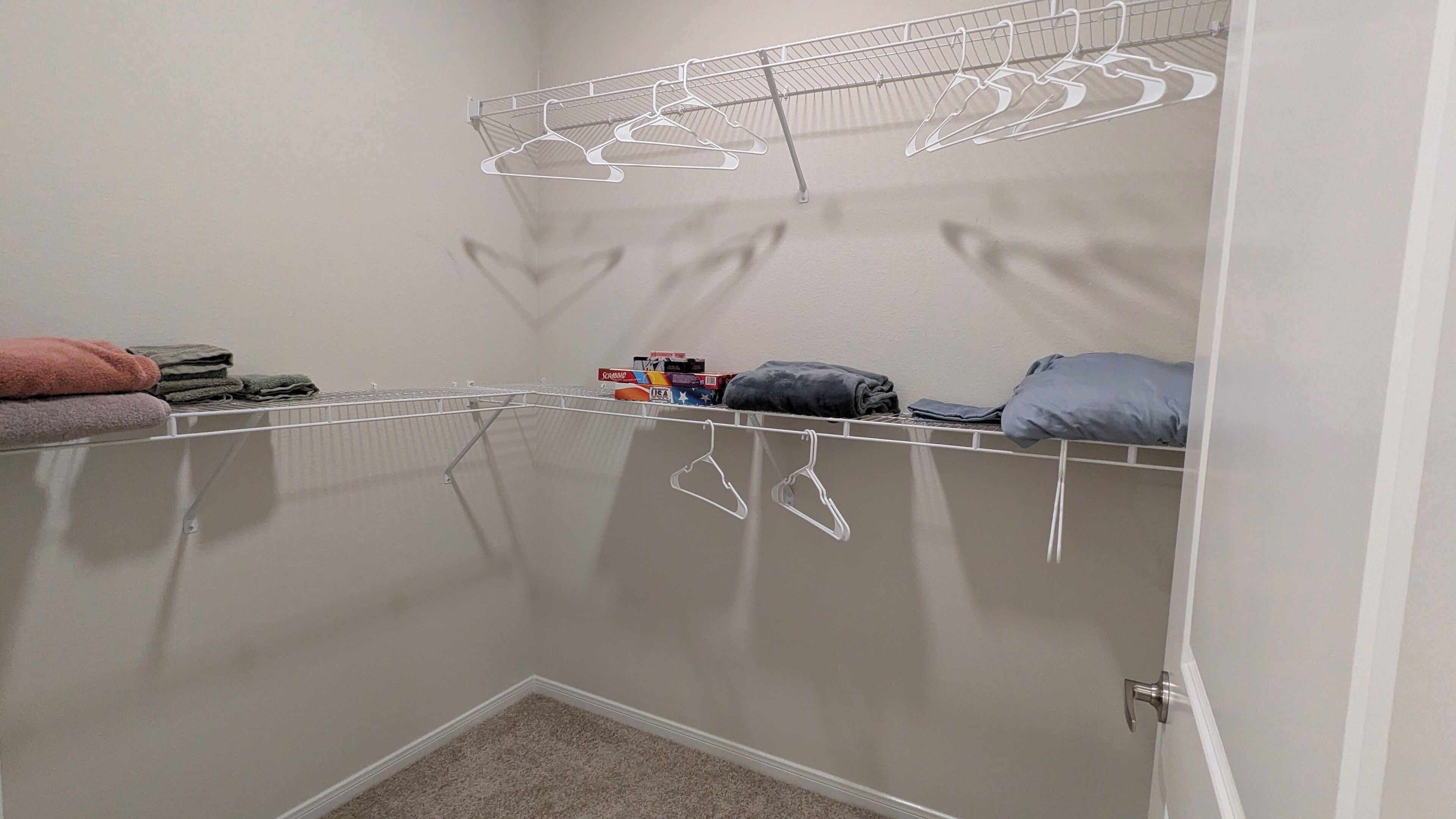 A laundry area with a metal drying rack, a shelf with folded clothes, and a small storage box.