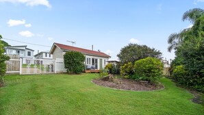 A residential property with a well-maintained lawn, a wooden fence, and a small garden area.