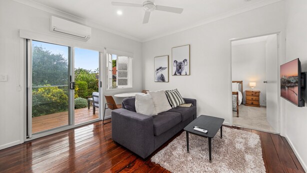 A modern living room with a grey sofa, a coffee table, and a large window with a view of greenery.
