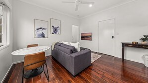 A modern living room with a grey sofa, a round white table, and a ceiling fan.