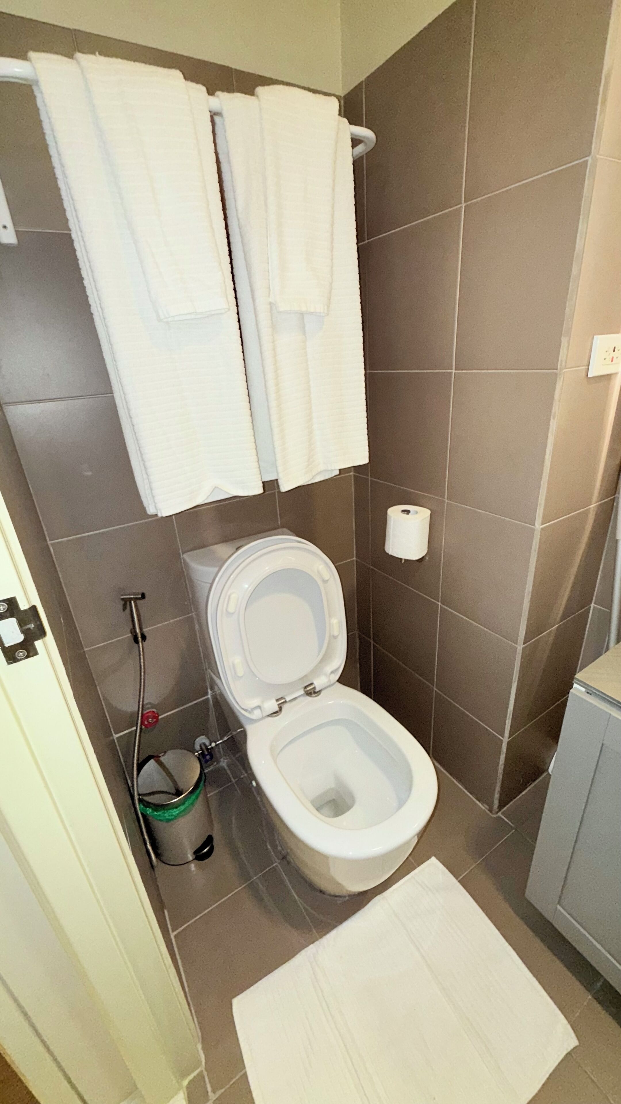 A bathroom with a toilet, a shower, and a sink. There are two white towels hanging on a rack.