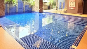 Ein Hallenbad mit Fliesenboden und Holzbalkendecke.