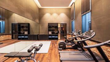 Un gimnasio moderno con equipamiento de ejercicio, un espejo grande y suelo de madera.