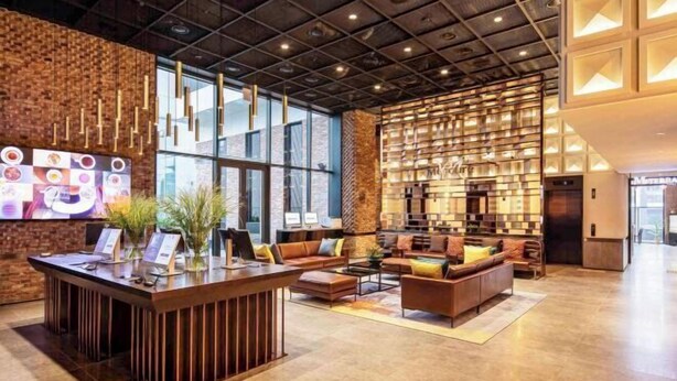 A modern lobby with a reception desk, seating area, and a large wall display.