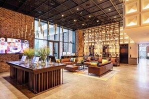 Eine moderne Lobby mit Empfangsschalter, Sitzgelegenheiten und einer großen Wandgestaltung.