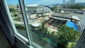 Vista dalla finestra su un cantiere edile con edifici, una grande struttura bianca e un edificio con tetto blu.
