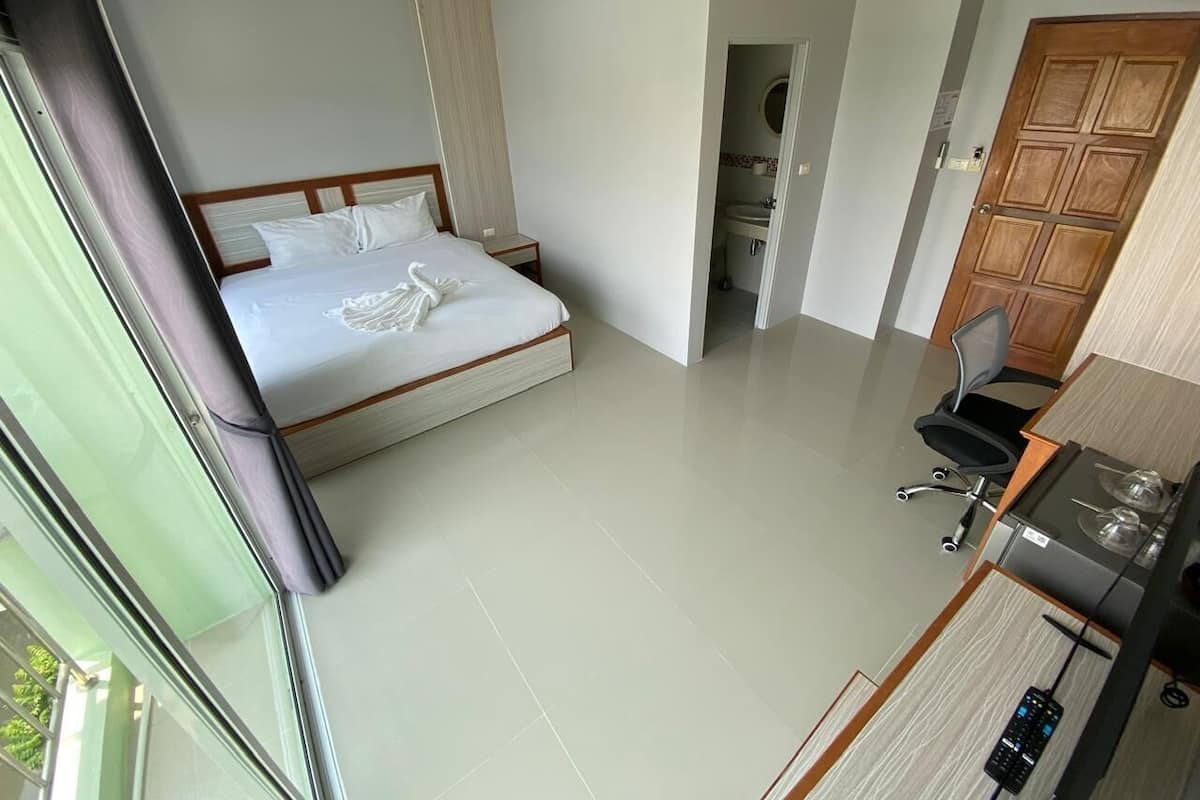 Ein Hotelzimmer mit einem Bett, einem kleinen Schreibtisch mit Stuhl, einer Küchenzeile und einem durchgegangenen Tür erkennbaren Badezimmer.