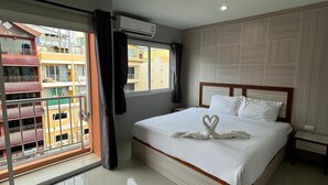 Camera d'albergo con un letto, una finestra con tende, un condizionatore d'aria e vista sui palazzi circostanti.