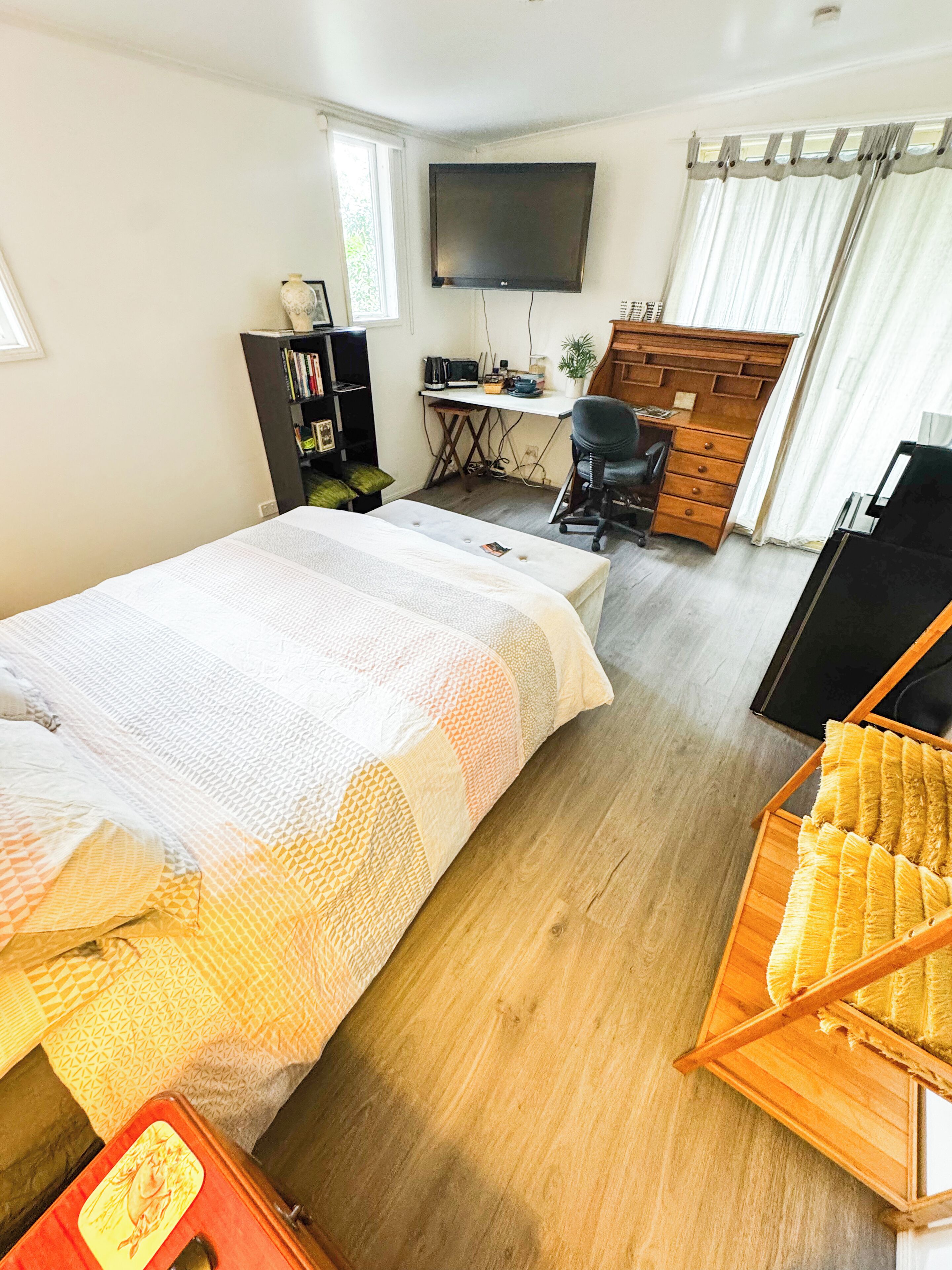 Une chambre à coucher comprenant un lit, un bureau, une chaise, une télévision et une armoire.