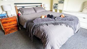 A bedroom with a bed, bedside tables, a wardrobe, and an air conditioning unit.