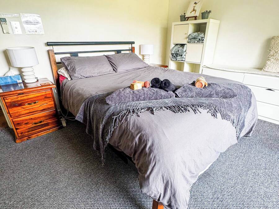 A bedroom with a bed, bedside tables, a wardrobe, and an air conditioning unit.