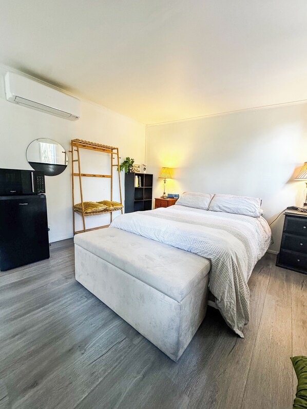 A bedroom with a bed, a bench, a wardrobe, a mirror, a shelf, and a lamp. - Paterson Skywalk & Bush Bedroom (Paterson)