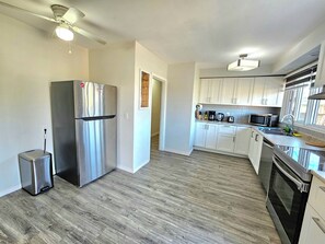 A modern kitchen with stainless steel appliances, white cabinets, and a wooden floor.