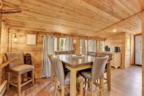 L’intérieur d’un chalet en bois comprend une table à manger, des chaises, un canapé et un coin café.