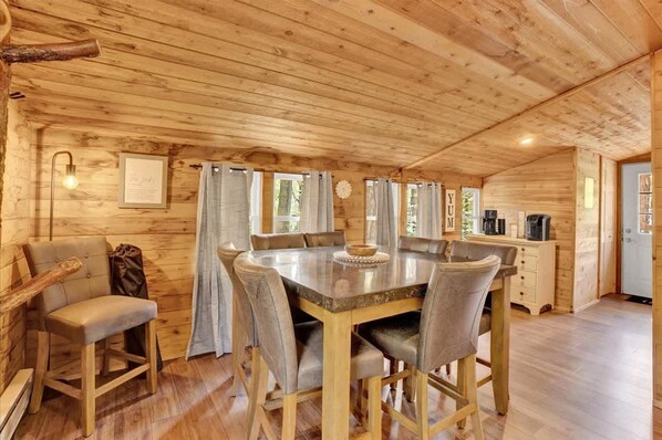 L’intérieur d’un chalet en bois comprend une table à manger, des chaises, un canapé et un coin café.