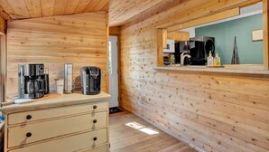 A wooden interior with a kitchenette, including a coffee maker, a microwave, and a sink.