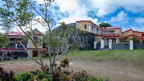 A residential area with multiple houses, a dirt path, and a tree in the foreground. - Le tropical Chez jeannette (Rodrigues Island)